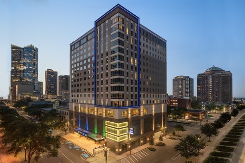 Downtown Houston hotel exterior at dusk near city skyline.