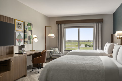Hotel guest room with two queen beds, workspace, and a view.