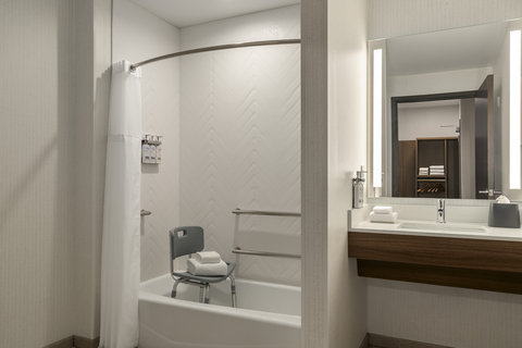 Accessible bathroom with a tub, grab bars, and bath seat.