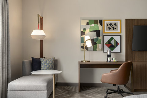 Guest room with a chaise lounge, work desk, and coffee station.