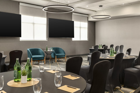 Meeting room with dual presentation screens and banquet seating.
