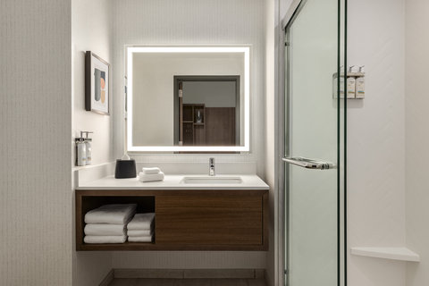 Guest bathroom with a walk-in shower and a lit vanity mirror.