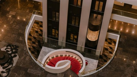 The hotel lobby featuring a grand staircase and capsule lifts