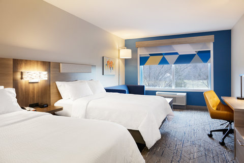 Modern hotel room with two beds, seating, and workspace.
