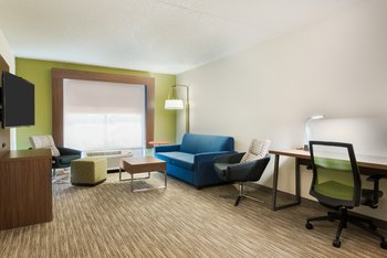 Living area of suite sleeper sofa work desk microwave and fridge