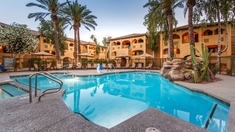 Outdoor pool surrounded by cacti and palm trees.