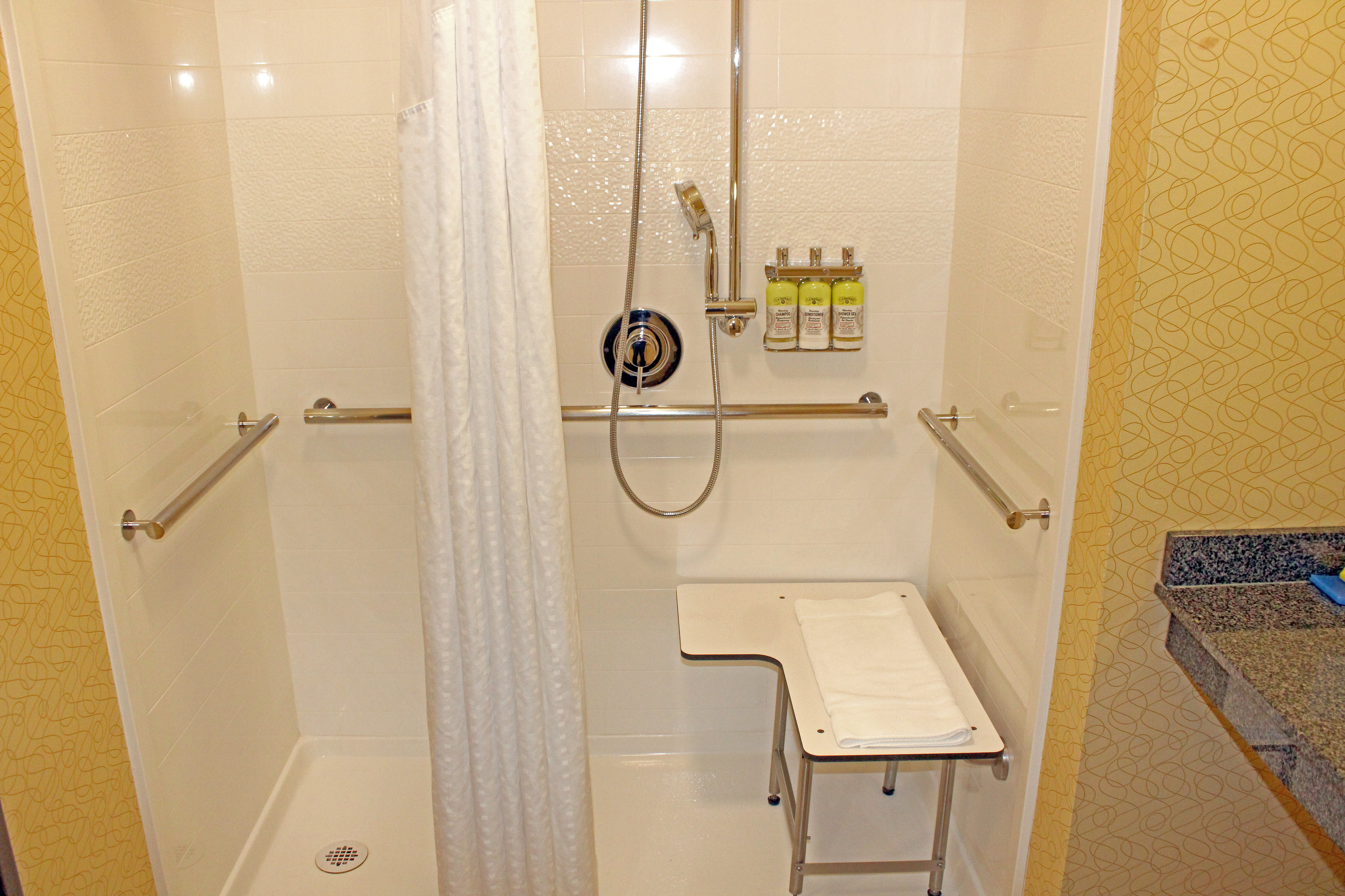 Roll-in shower with grab bars, seat and detachable shower wand.
