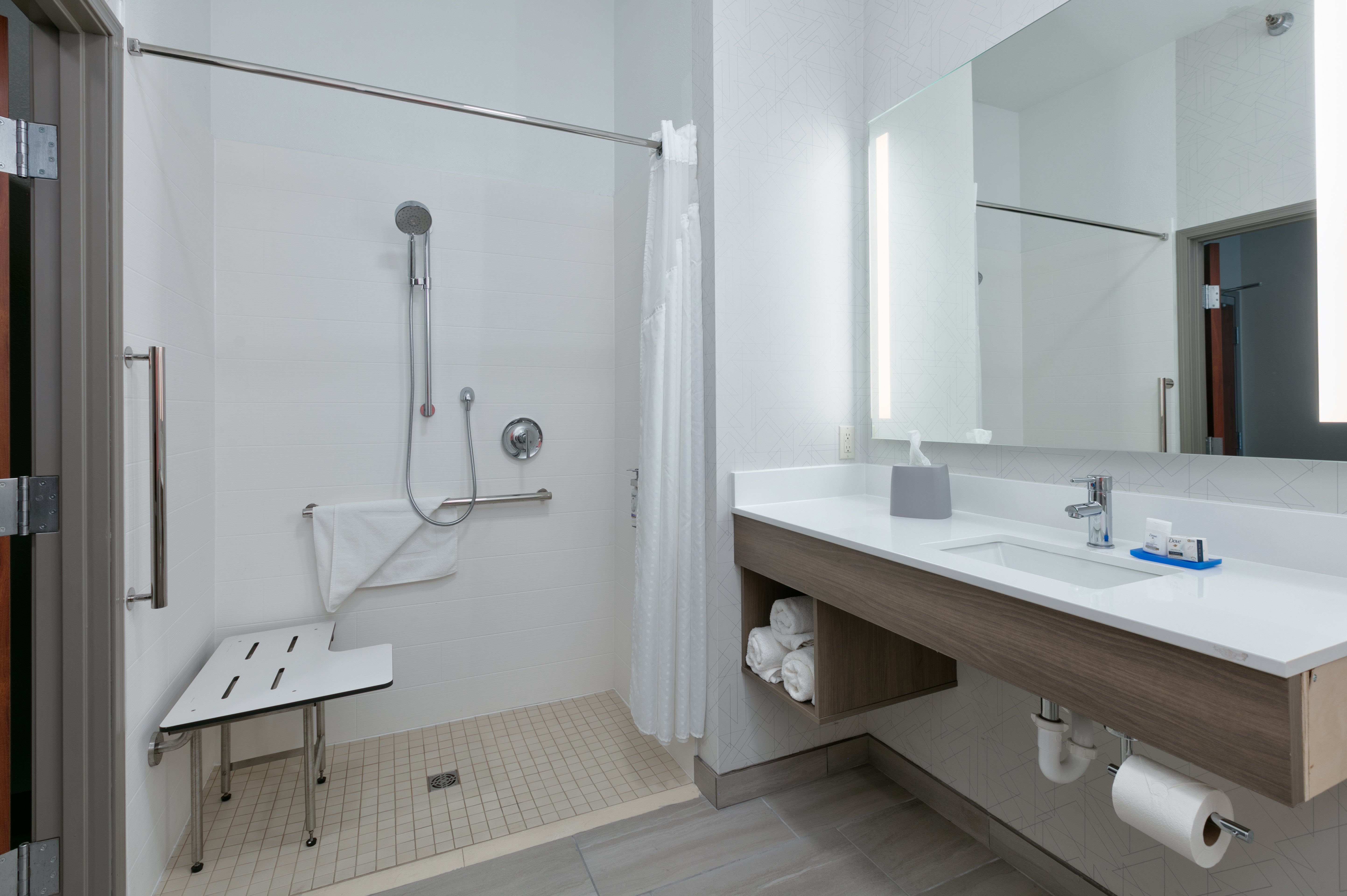Accessible bathroom with roll-in shower, seat and stability bars. 