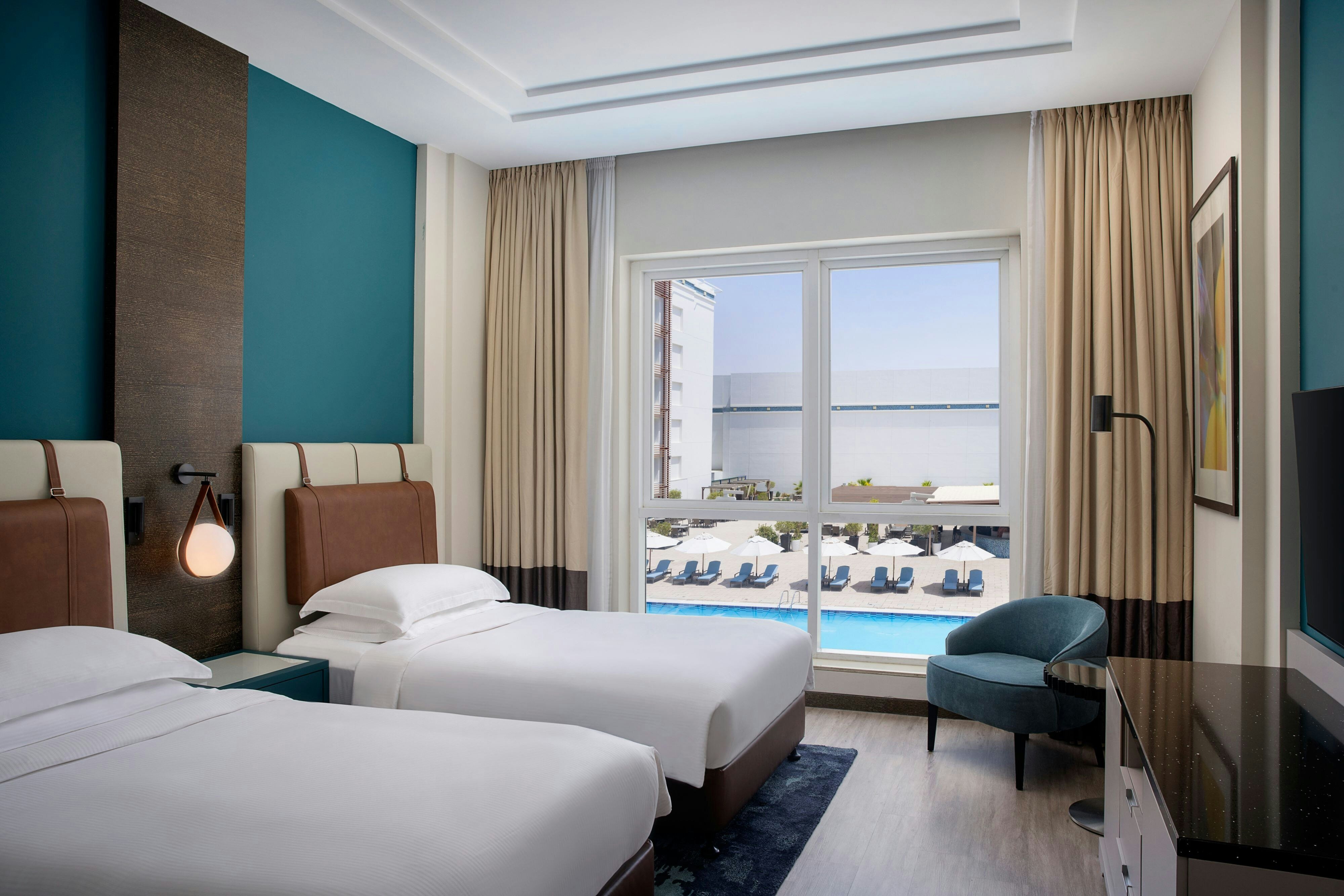 Four Points by Sheraton Al Ain-guestroom-Twin beds, sitting area and the pool view..jpg
